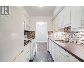 A kitchen with white cabinets and a stone backsplash.