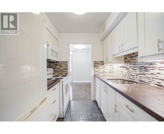 A kitchen with white cabinets and a stone backsplash.