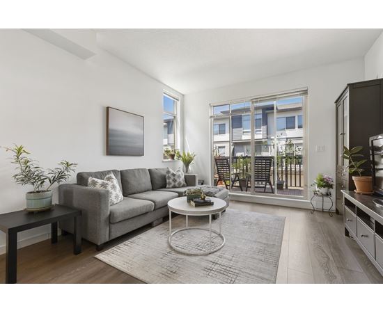 A living room with a grey couch, a coffee table, and a painting on the wall.