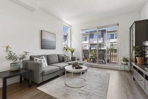 A living room with a grey couch, a coffee table, and a painting on the wall.