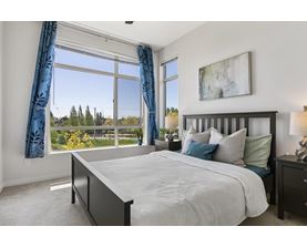 A bedroom with a large bed and a view of trees outside the window.