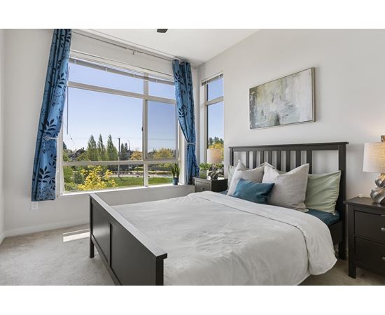 A bedroom with a large bed and a view of trees outside the window.