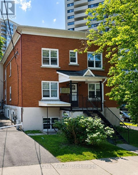 A red brick house with a white trim and a black railing on the balcony.
