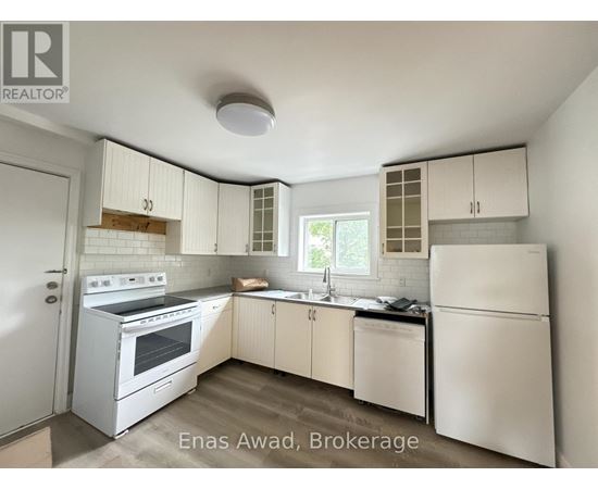A white kitchen with a refrigerator, oven, and sink.