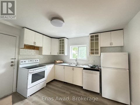 A white kitchen with a refrigerator, oven, and sink.
