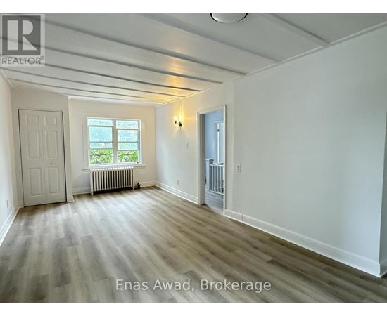 A spacious room with wood flooring and white walls.