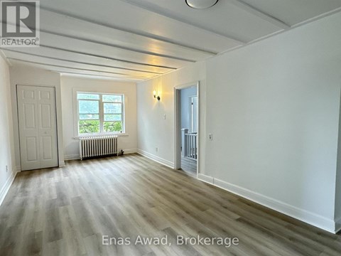 A spacious room with wood flooring and white walls.