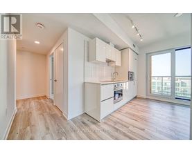 A well-lit kitchen with white cabinets and a wooden floor.