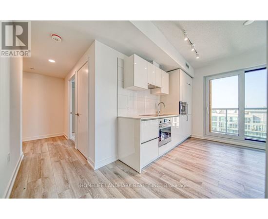 A well-lit kitchen with white cabinets and a wooden floor.