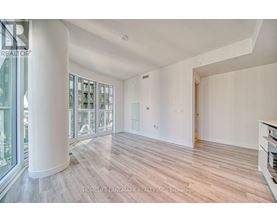 A spacious room with wooden flooring and a large window.