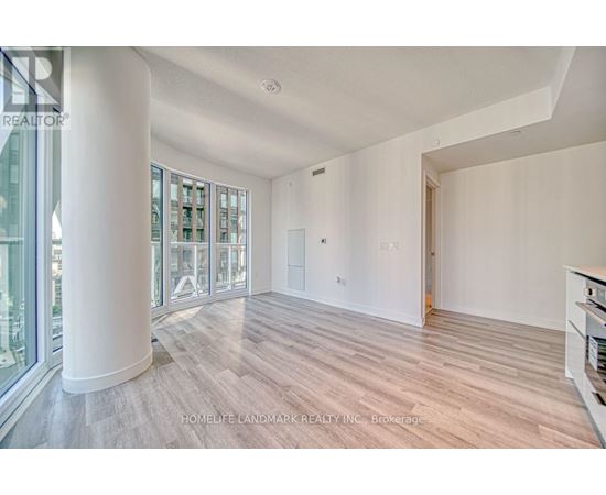A spacious room with wooden flooring and a large window.