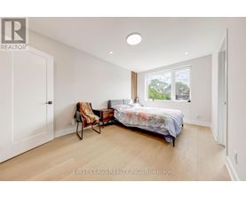A bedroom with a bed, chair, and window.