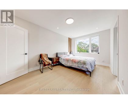 A bedroom with a bed, chair, and window.