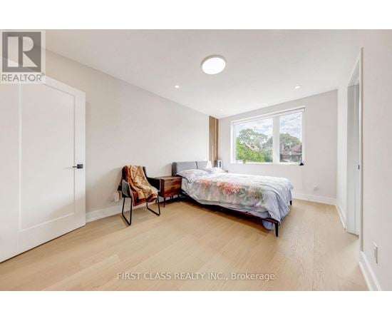 A bedroom with a bed, chair, and window.