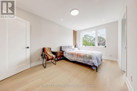 A bedroom with a bed, chair, and window.