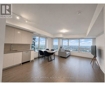 A spacious room with a dining table and chairs, a kitchen area, and a large window with a view of the city.