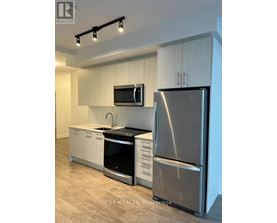A modern kitchen with a stainless steel refrigerator, microwave, and oven.