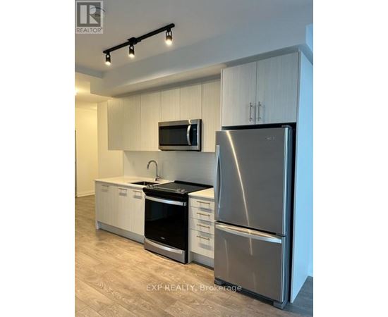 A modern kitchen with a stainless steel refrigerator, microwave, and oven.