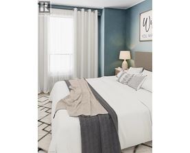 A bedroom with a white bed and a grey blanket.