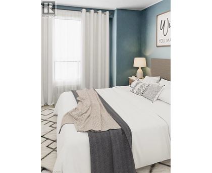 A bedroom with a white bed and a grey blanket.