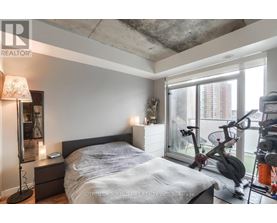 A bedroom with a bed, nightstand, and exercise equipment.