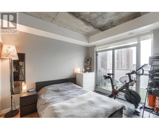A bedroom with a bed, nightstand, and exercise equipment.