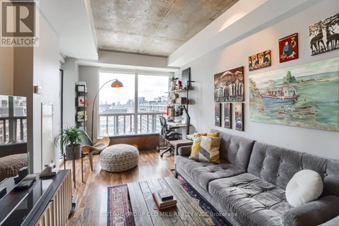 A living room with a grey couch and a large window.