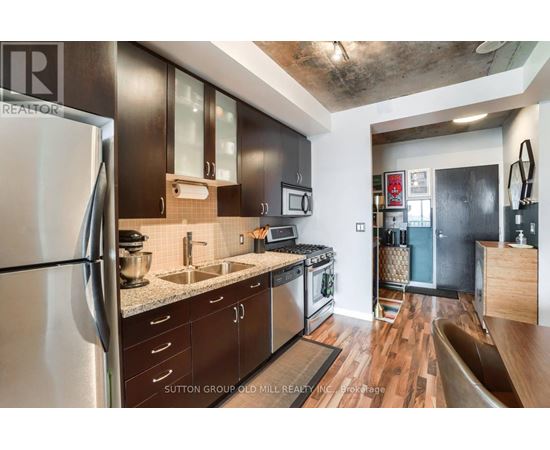 A modern kitchen with dark wood cabinets and stainless steel appliances.