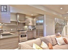 A modern kitchen with a stainless steel oven and a couch with throw pillows.