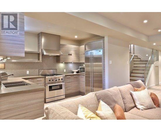A modern kitchen with a stainless steel oven and a couch with throw pillows.