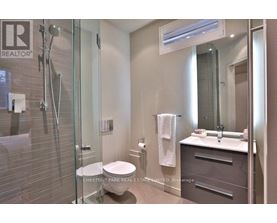 A bathroom with a glass shower stall, toilet, and sink.