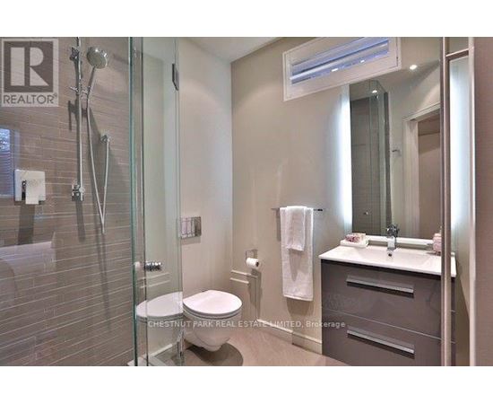 A bathroom with a glass shower stall, toilet, and sink.
