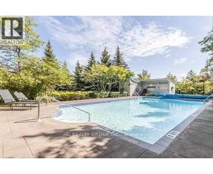 A pool surrounded by trees and a house in the background.