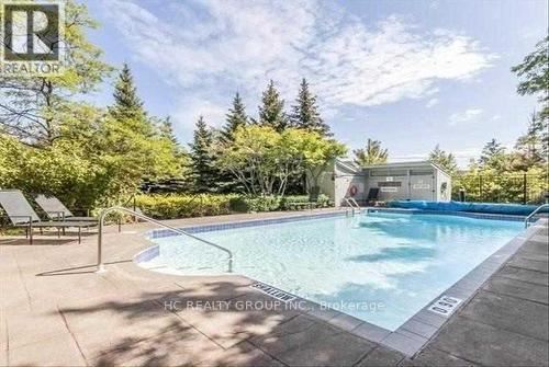 A pool surrounded by trees and a house in the background.
