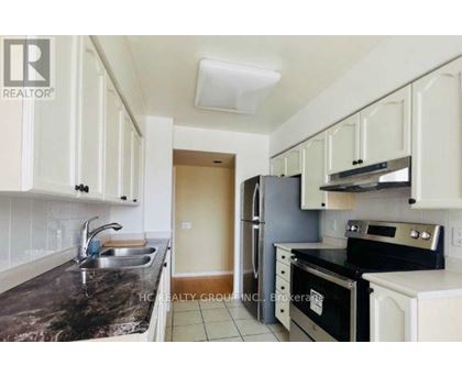 A kitchen with white cabinets and black countertops.