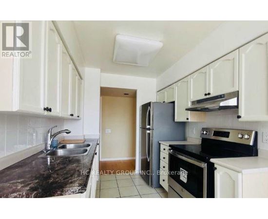 A kitchen with white cabinets and black countertops.