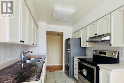 A kitchen with white cabinets and black countertops.