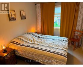A bedroom with a bed, a chair, and pictures on the wall.