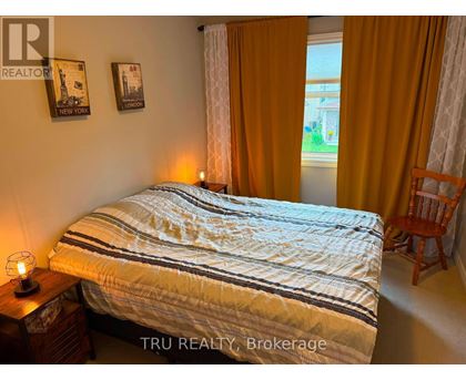 A bedroom with a bed, a chair, and pictures on the wall.