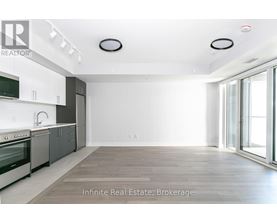 A spacious kitchen with white cabinets and a large window.