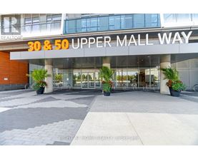 The entrance to the 30 & 50 Upper Mall Way building with a glass door and a plant on the sidewalk.