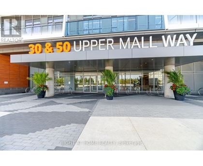 The entrance to the 30 & 50 Upper Mall Way building with a glass door and a plant on the sidewalk.