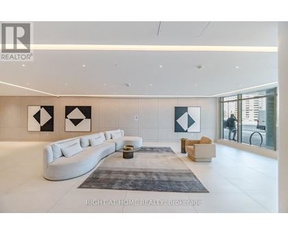 A spacious living room with a white sofa and a grey rug.