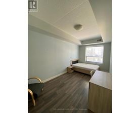 A bedroom with a bed, chair, and window.