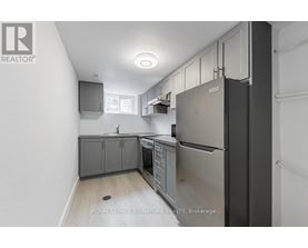 A kitchen with a refrigerator, sink, and cabinets.