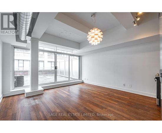 A large, empty room with wood flooring and a large window.