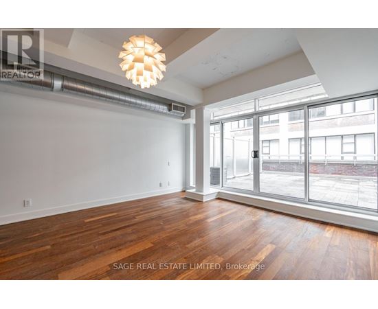 A room with wooden floors and a large window overlooking a city street.