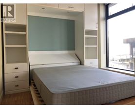 A bedroom with a bed, drawers, and a wardrobe.