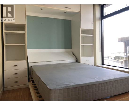A bedroom with a bed, drawers, and a wardrobe.
