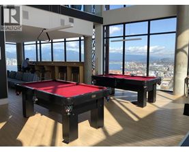 A man is working on a pool table in a room with large windows.